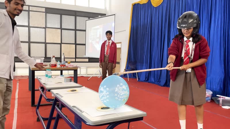 Student holding a rod towards a balloon in an electrostatics demonstration