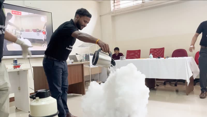 Presenter pouring liquid nitrogen, creating a large white vapour cloud