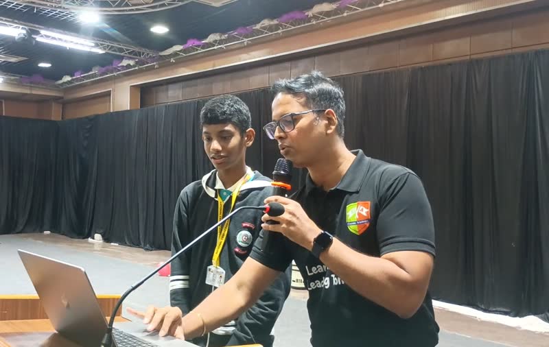 A student speaks into a microphone while a Manthan educator assists