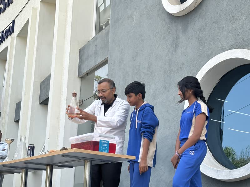 An educator demonstrates an experiment outdoors with two students