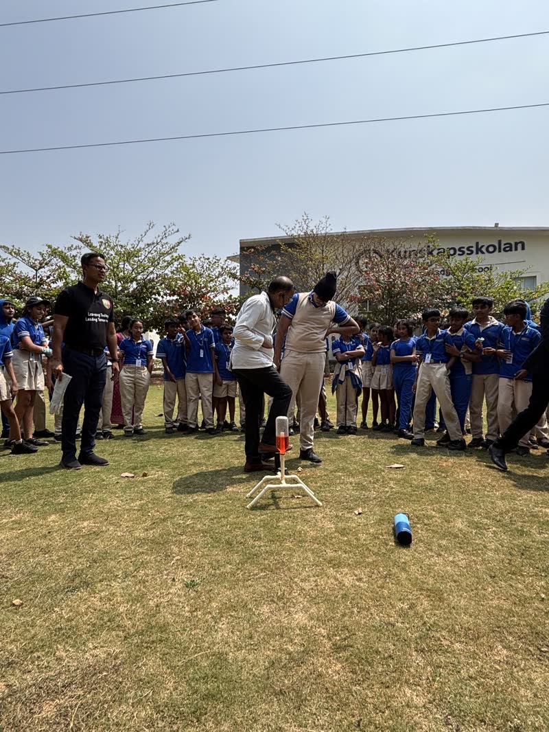 Outdoor rocket launch demonstration with students watching